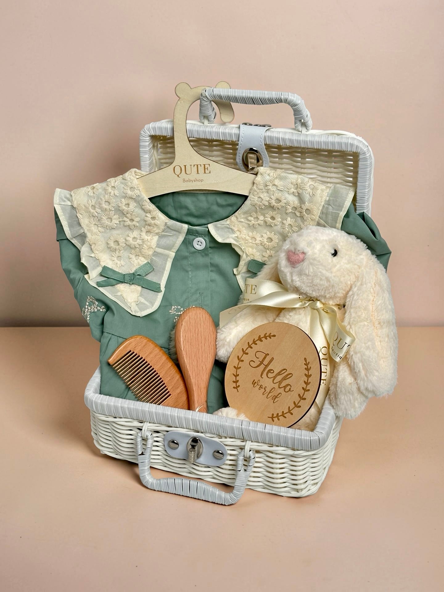 Luxury sage green baby girl gift set in white woven suitcase hamper with lace floral collar dress, plush bunny toy, wooden milestone disc, and hairbrush comb set by Qute Gifts Doha Qatar