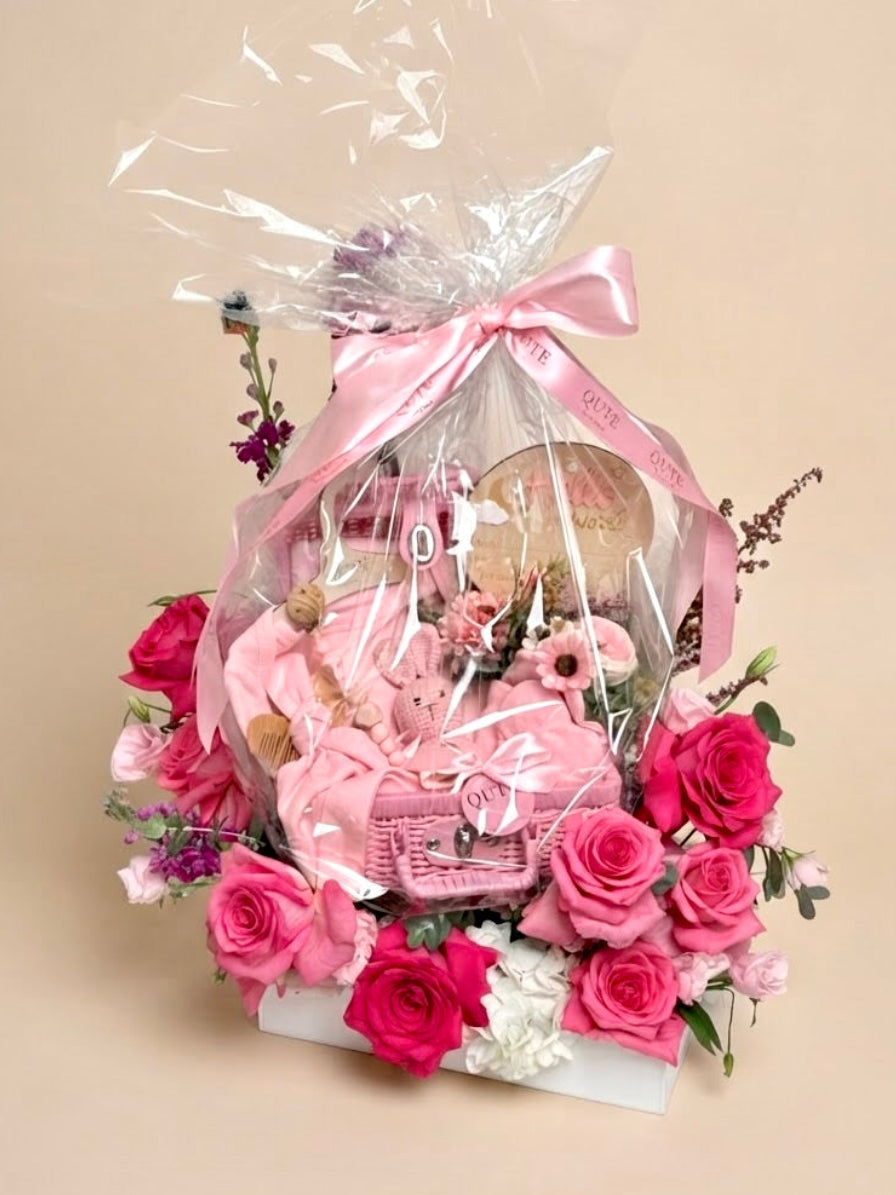 Luxury pink newborn gift basket and floral base arrangement featuring floral art by Plaza Hollandi, curated by Qatar's premier baby gift company.
