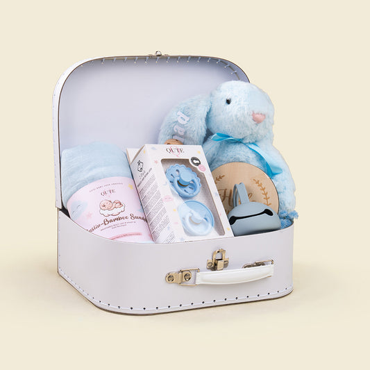 Plaza Hollandi x Qute luxury baby boy gift set in white vintage keepsake suitcase with plush blue bunny, bamboo swaddle blanket, pacifiers, and wooden milestone plaque for baby boy gifts in Doha Qatar