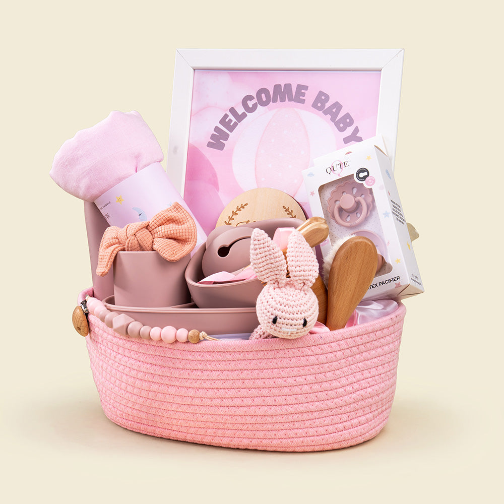 Plaza Hollandi x Qute luxury baby girl gift set in pink woven rope basket featuring dusty rose silicone weaning tableware, bamboo swaddle, and accessories for baby girl gifts in Doha Qatar