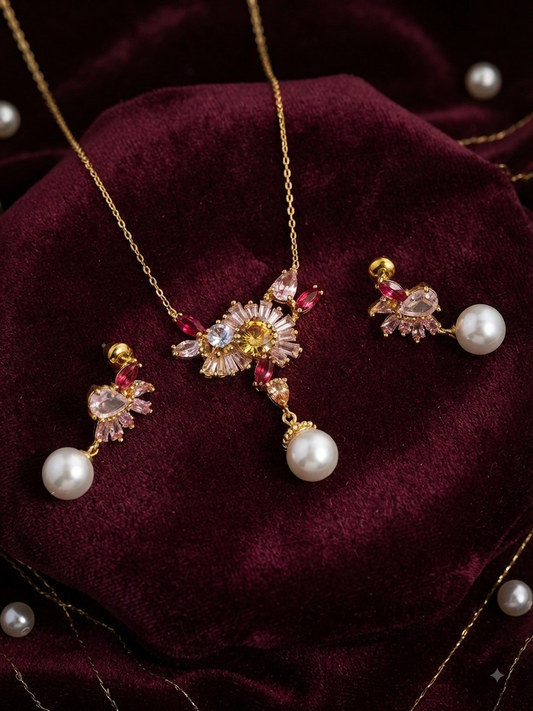 Elara jewelry set displayed on deep maroon velvet featuring a gold chain necklace with a floral crystal cluster pendant in shades of pink, yellow, and clear stones with a hanging white pearl drop, and matching screw-back earrings with crystal clusters and pearl drops in Doha Qatar