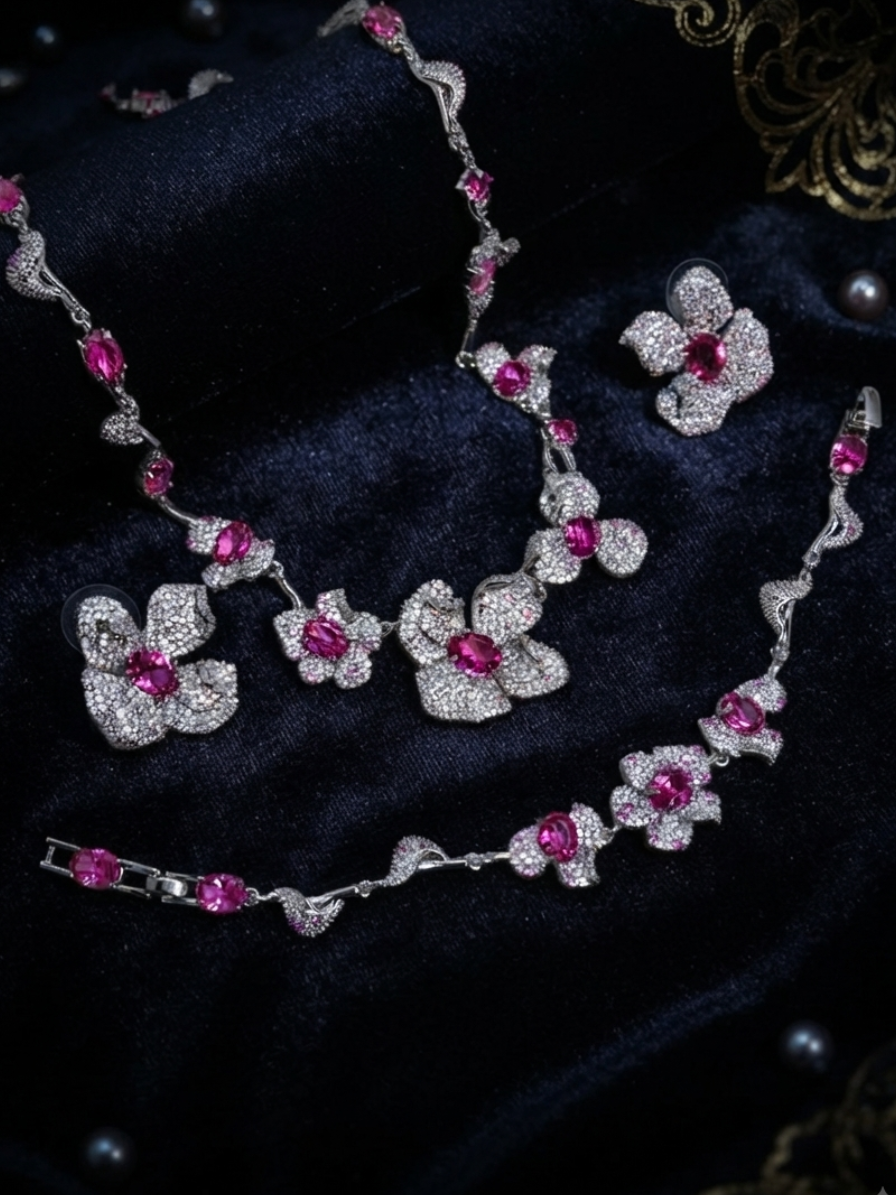 Elara jewelry set displayed on dark velvet featuring a silver-plated floral statement necklace with brilliant fuchsia pink crystal centers and heavy pave-encrusted petals, a matching link bracelet, and coordinating stud earrings in Doha Qatar