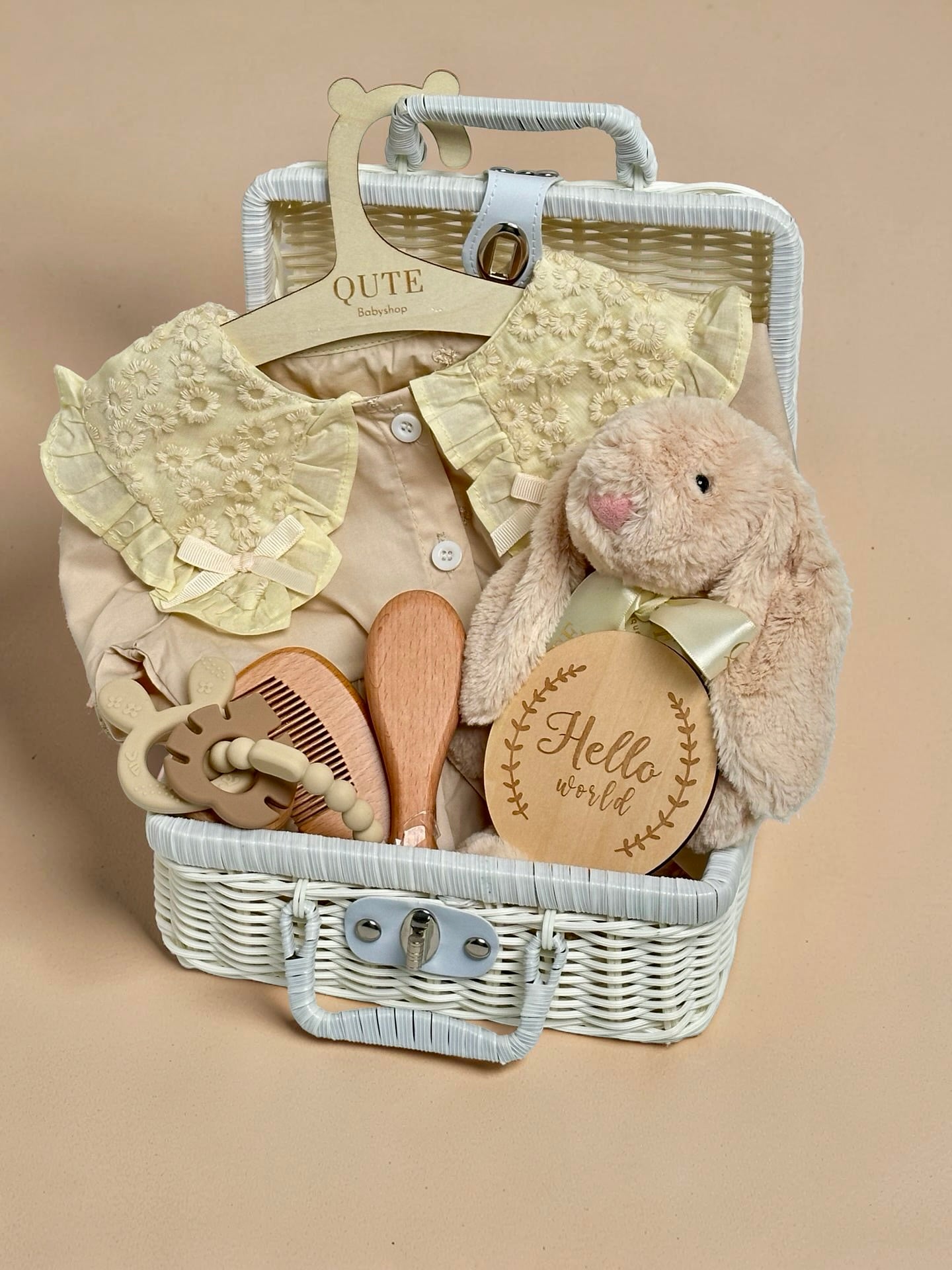 Yellow baby girl gift set in white woven suitcase hamper with floral lace collar dress, plush bunny toy, wooden hairbrush comb set, silicone teether ring, and wooden milestone disc by Qute Gifts Doha Qatar