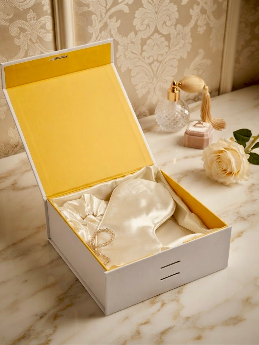 Luxury 100% mulberry silk self-care gift set in ivory by Qute Qatar, featuring an ivory silk pillowcase, eye mask, and scrunchie inside a luxury gift box for postpartum and birthday gifting in Doha.