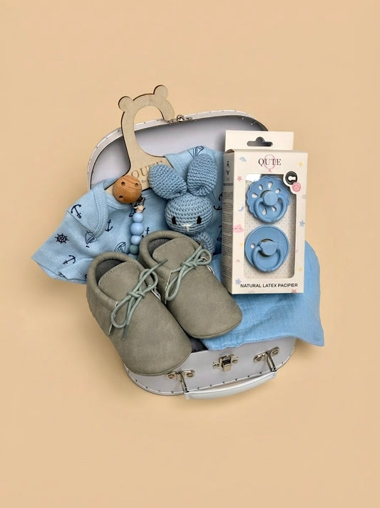 Luxury baby boy newborn gift set in a white keepsake suitcase by Qute Qatar, featuring a 1-3 months nautical bodysuit, moccasins, natural latex pacifiers, and a crocheted bunny for delivery in Doha.