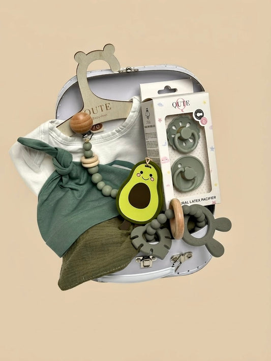 Luxury newborn baby gift set in a white keepsake suitcase by Qute Qatar, featuring a 3-6 months sage green outfit, avocado teether, pacifiers, and teething accessories for delivery in Doha.