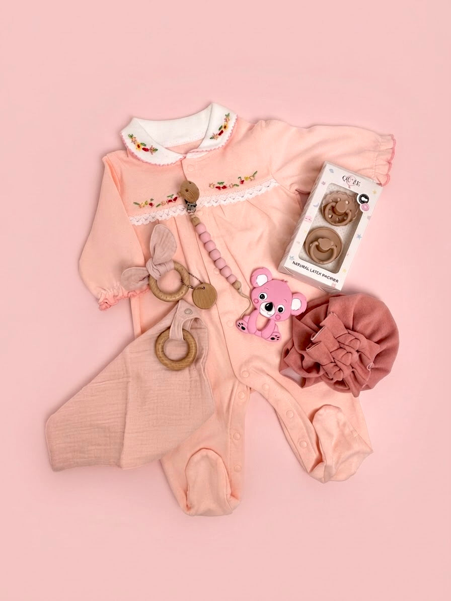 Luxury baby girl newborn gift set in a floral keepsake suitcase by Qute Qatar, featuring a 3-6 months full-leg romper, koala teether, pacifiers, and wooden accessories for delivery in Doha.