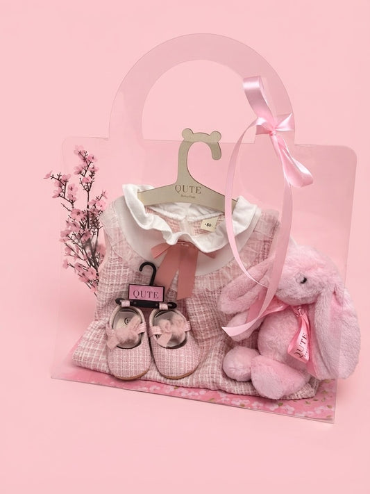 Luxury first birthday baby girl gift set in a clear presentation bag by Qute Qatar, featuring a 12-18 months pink tweed dress, matching shoes, and a plush pink bunny for delivery in Doha.