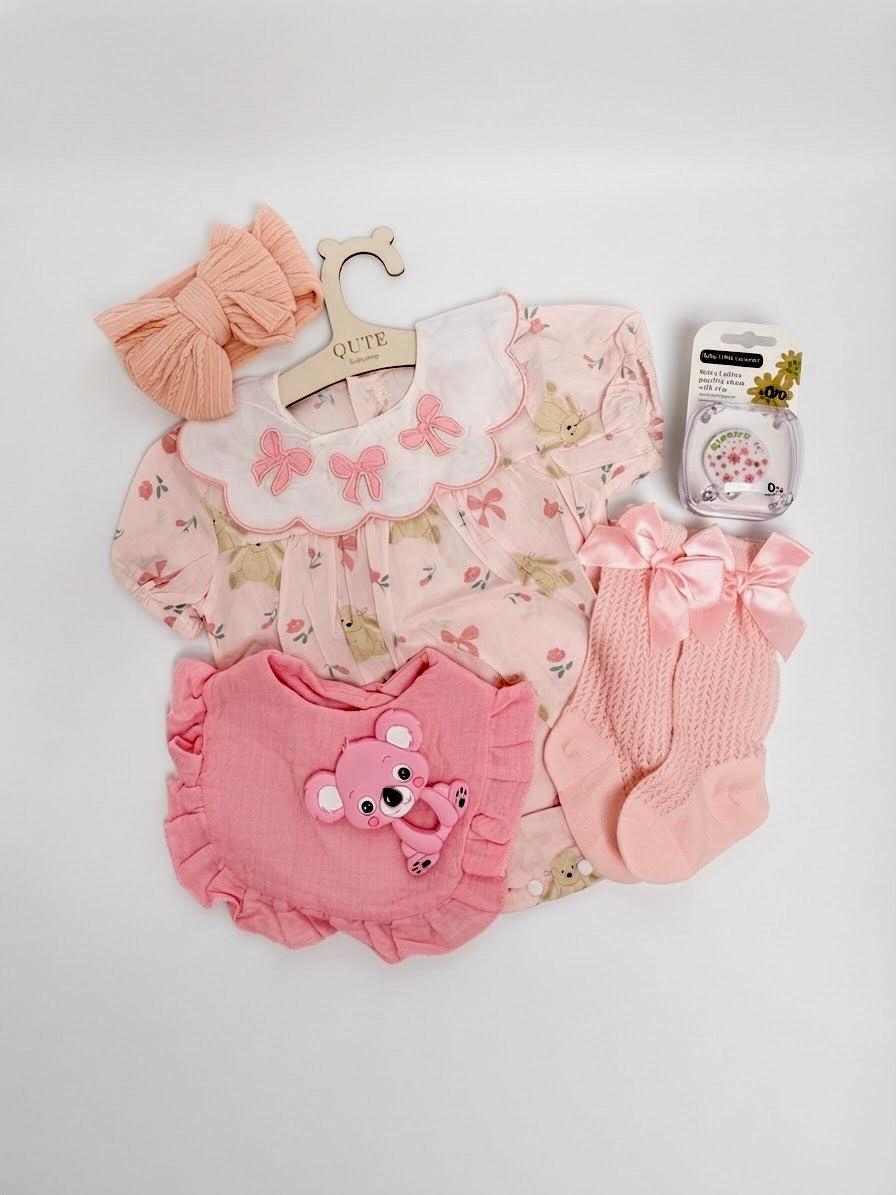 Luxury baby girl newborn gift set in a white keepsake suitcase by Qute Qatar, featuring a 3-6 months pink floral outfit, koala teether, hair bows, and accessories for delivery in Doha.