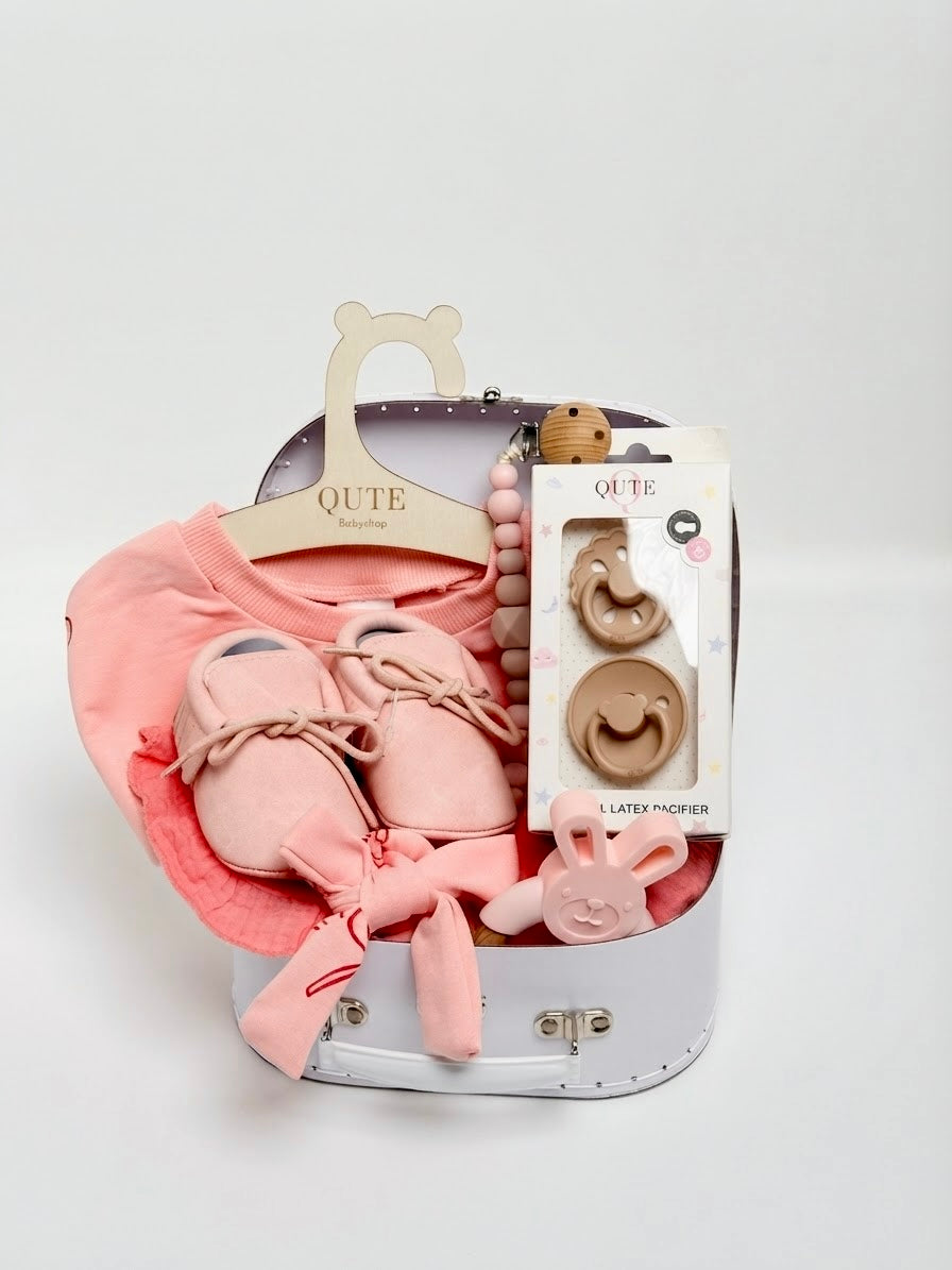 Luxury baby girl newborn gift set in a keepsake suitcase box by Qute Qatar, featuring a 3-6 months bow-print outfit, soft shoes, bunny teether, and natural latex pacifiers for delivery in Doha.