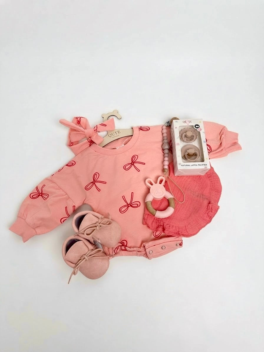 Luxury baby girl newborn gift set in a keepsake suitcase box by Qute Qatar, featuring a 3-6 months bow-print outfit, soft shoes, bunny teether, and natural latex pacifiers for delivery in Doha.