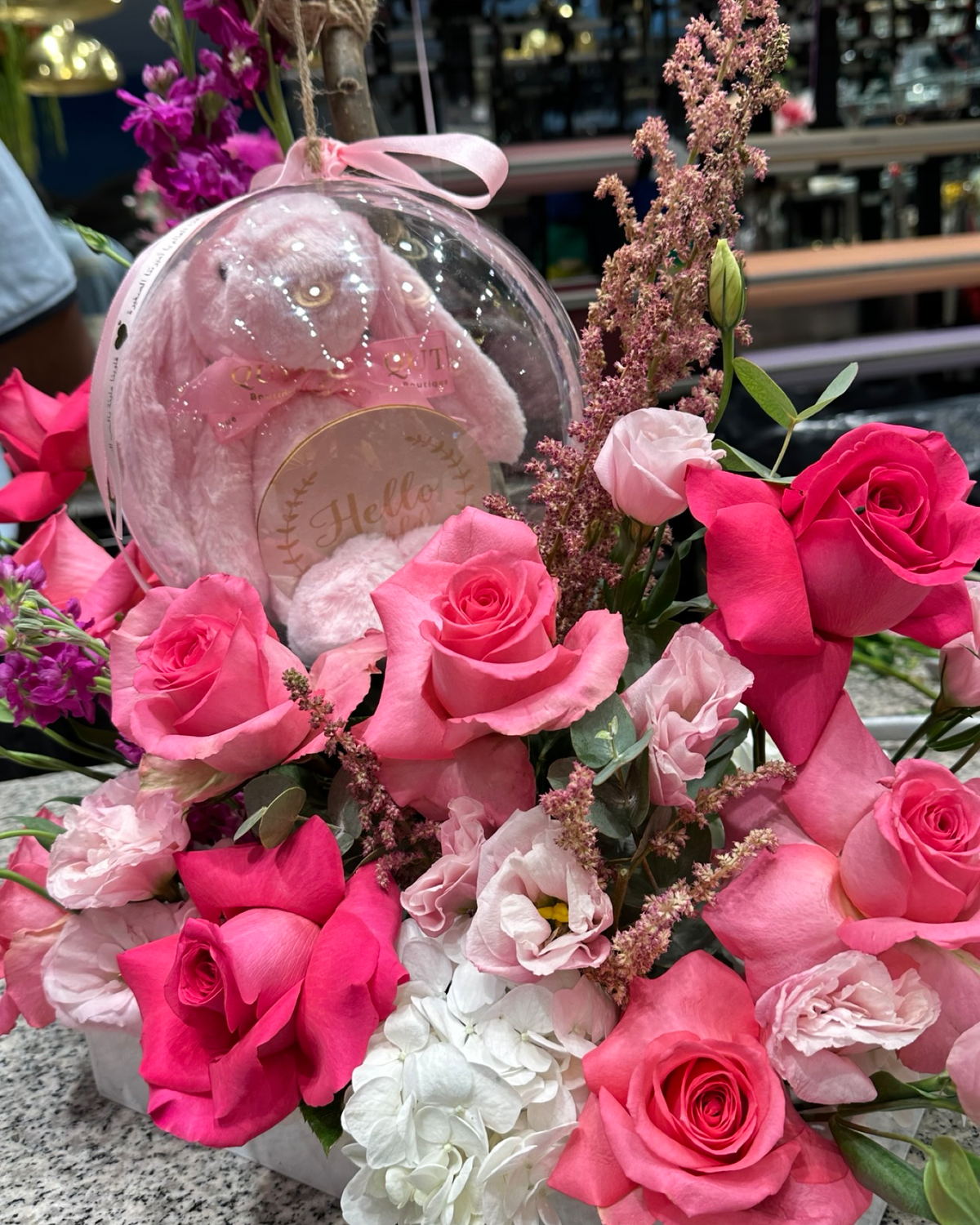 Plaza Hollandi collaborative baby gift arrangement by Story Stems featuring pink roses and a keepsake bubble inspired by Seju from Ezdan Mall.   