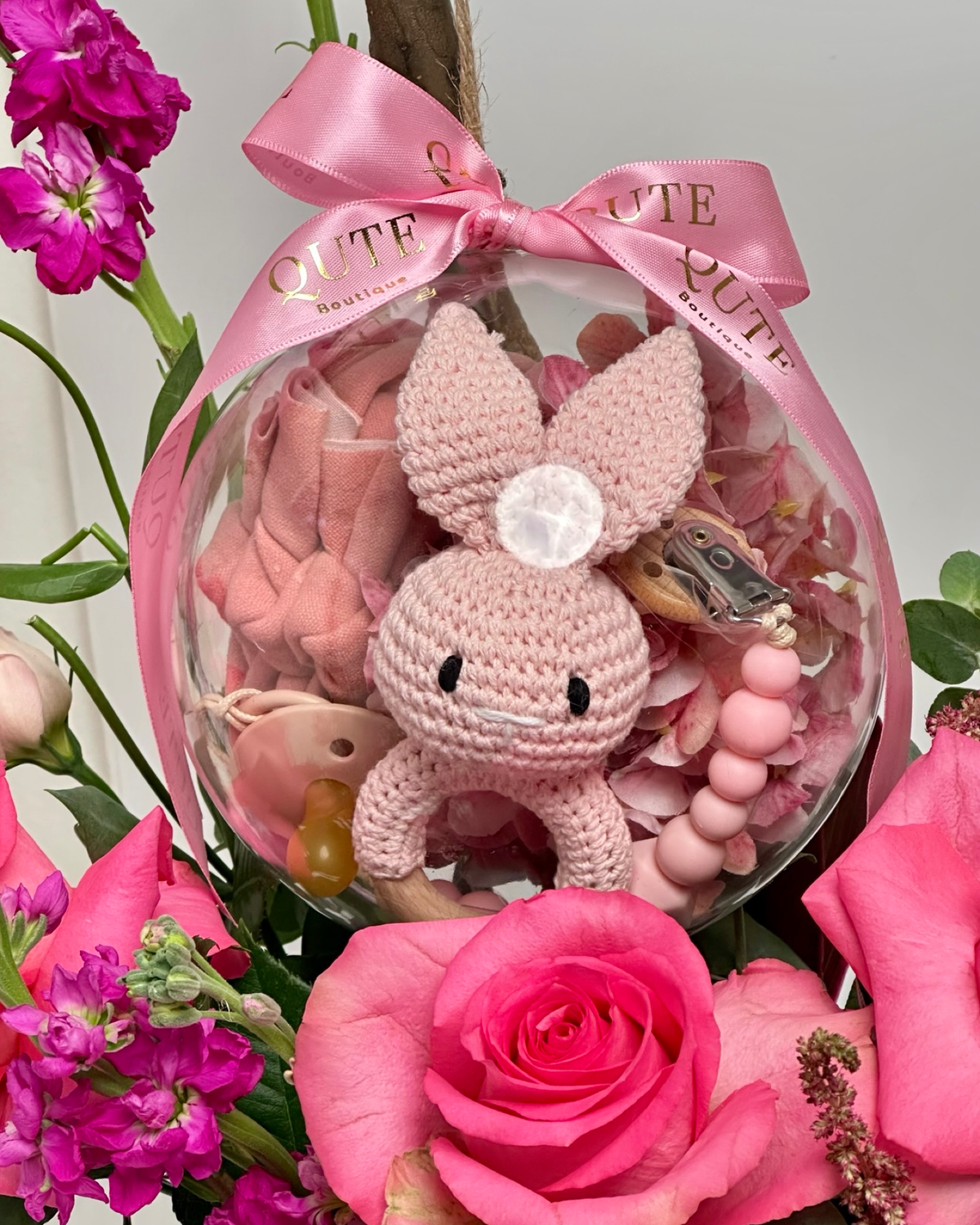 Same-day baby girl gift box featuring luxury pink roses and an acrylic keepsake bubble with a handmade crochet bunny for welcoming a newborn.   