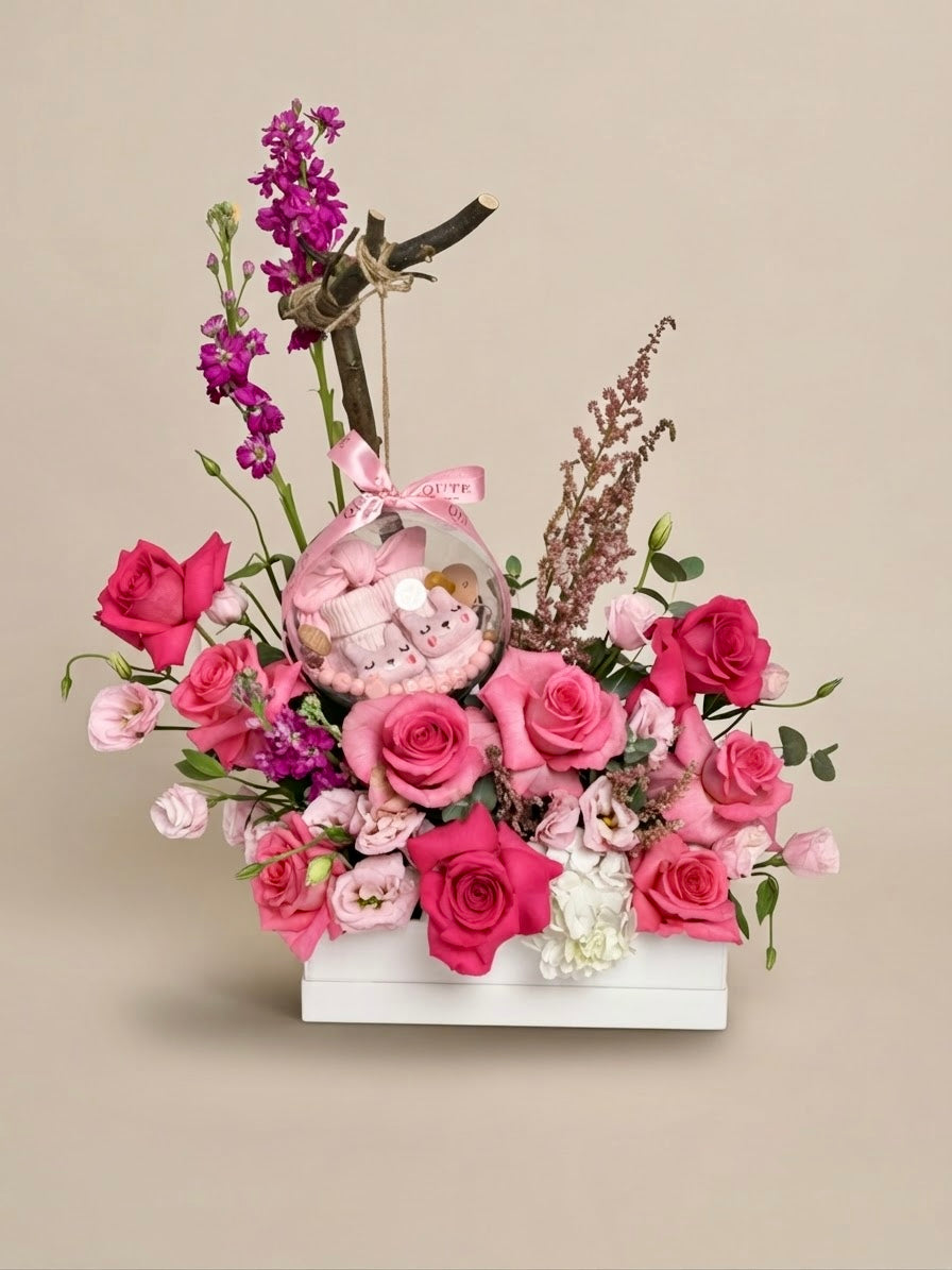 Same-day or custom baby girl gift box featuring luxury pink roses and an acrylic keepsake bubble packed with adorable newborn clothing items for welcoming a new baby.   