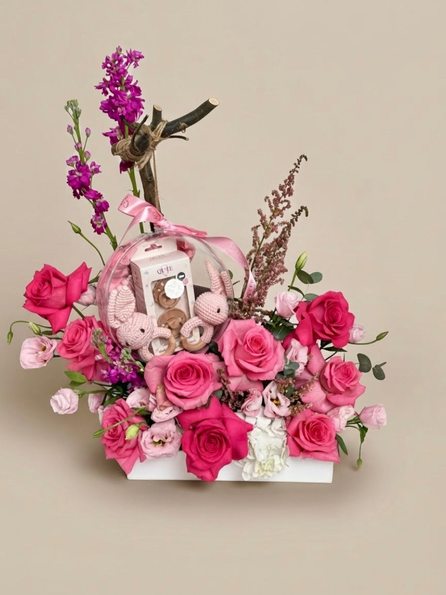 Baby Bloom Bubble twin baby girls flower arrangement featuring pink roses and an acrylic keepsake bubble filled with dual crochet bunny rattles and pacifiers.