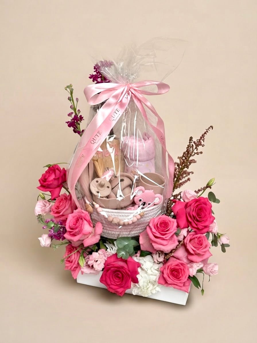 Luxury pink newborn gift basket and floral base arrangement featuring floral art by Plaza Hollandi, curated by Qatar's premier baby gift company.