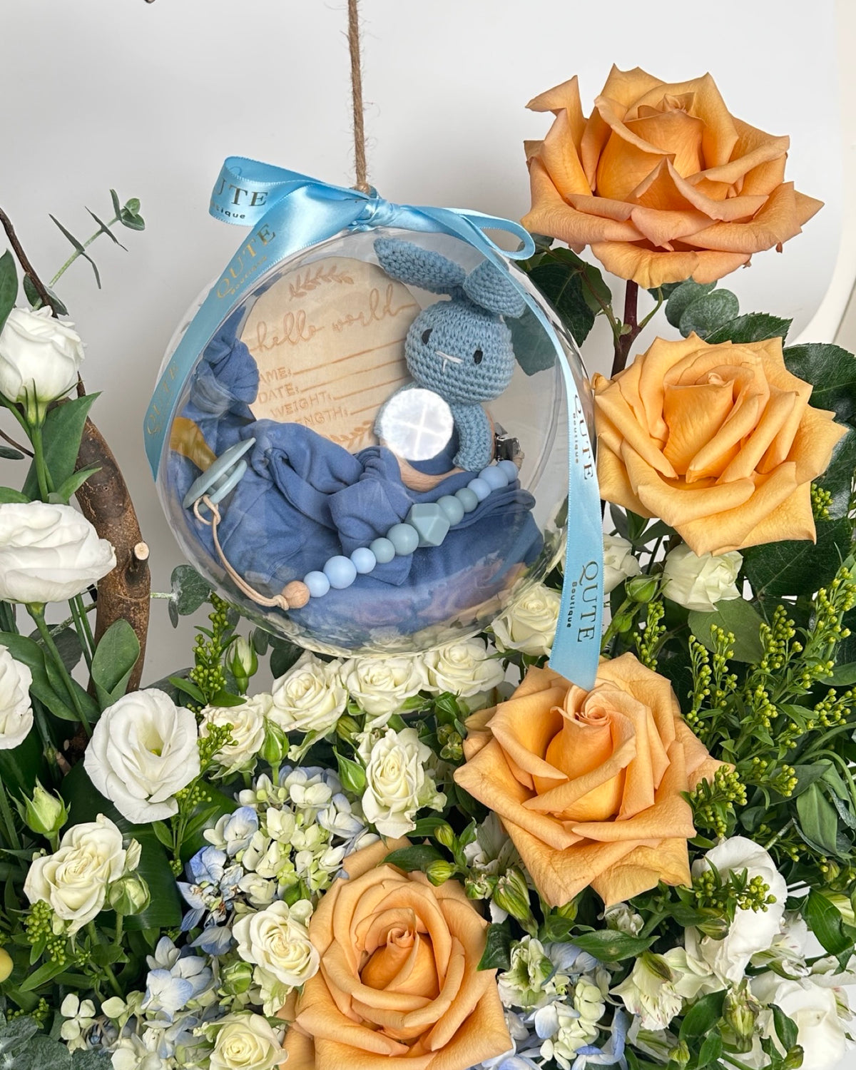 Special baby boy gift box featuring luxury champagne roses and an acrylic keepsake bubble packed with custom newborn items for welcoming a newborn son.